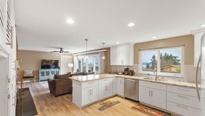 Una cocina moderna con armarios blancos, una isla grande y vistas al exterior.