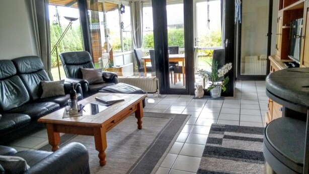 Un salon avec un canapé en cuir noir, une table basse en bois et un coin repas comprenant une table et des chaises.