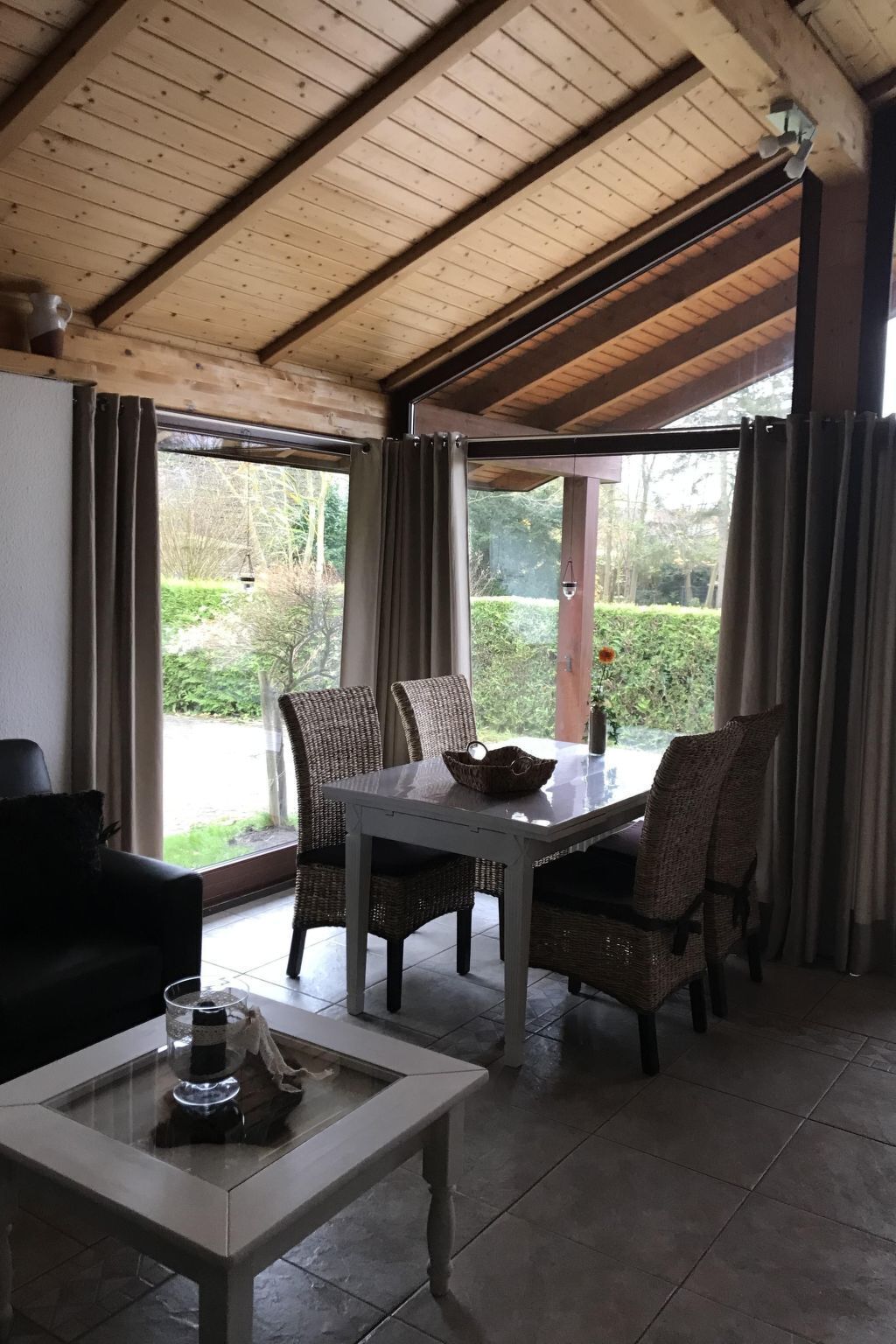 A dining area with a table and chairs, a coffee table, and a view of greenery outside.