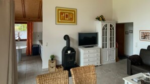 Een woonkamer met een open haard, televisie en zithoek.