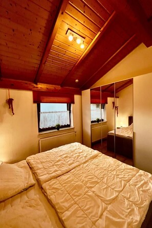 A bedroom with a large bed, a window, a radiator, and a mirror. - Haus Luna by Interhome (Burhave)