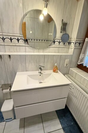 A bathroom with a white sink, a mirror, and a toilet. - Haus Luna by Interhome (Burhave)