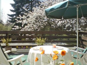 A patio with a table set for two, surrounded by white chairs and a green umbrella. - Appartement mit Dachterrasse by Interhome (Burhave)