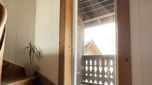 Eine Holztreppe führt zu einem Fenster mit Blick auf einen Balkon.
