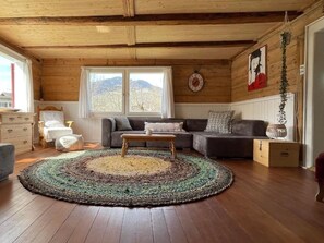 A cozy living room with a wooden ceiling, a large window, a sofa, a coffee table, and a rug. - Casa Marili, das charmante Ferienhaus by Interhome (Sevgein)