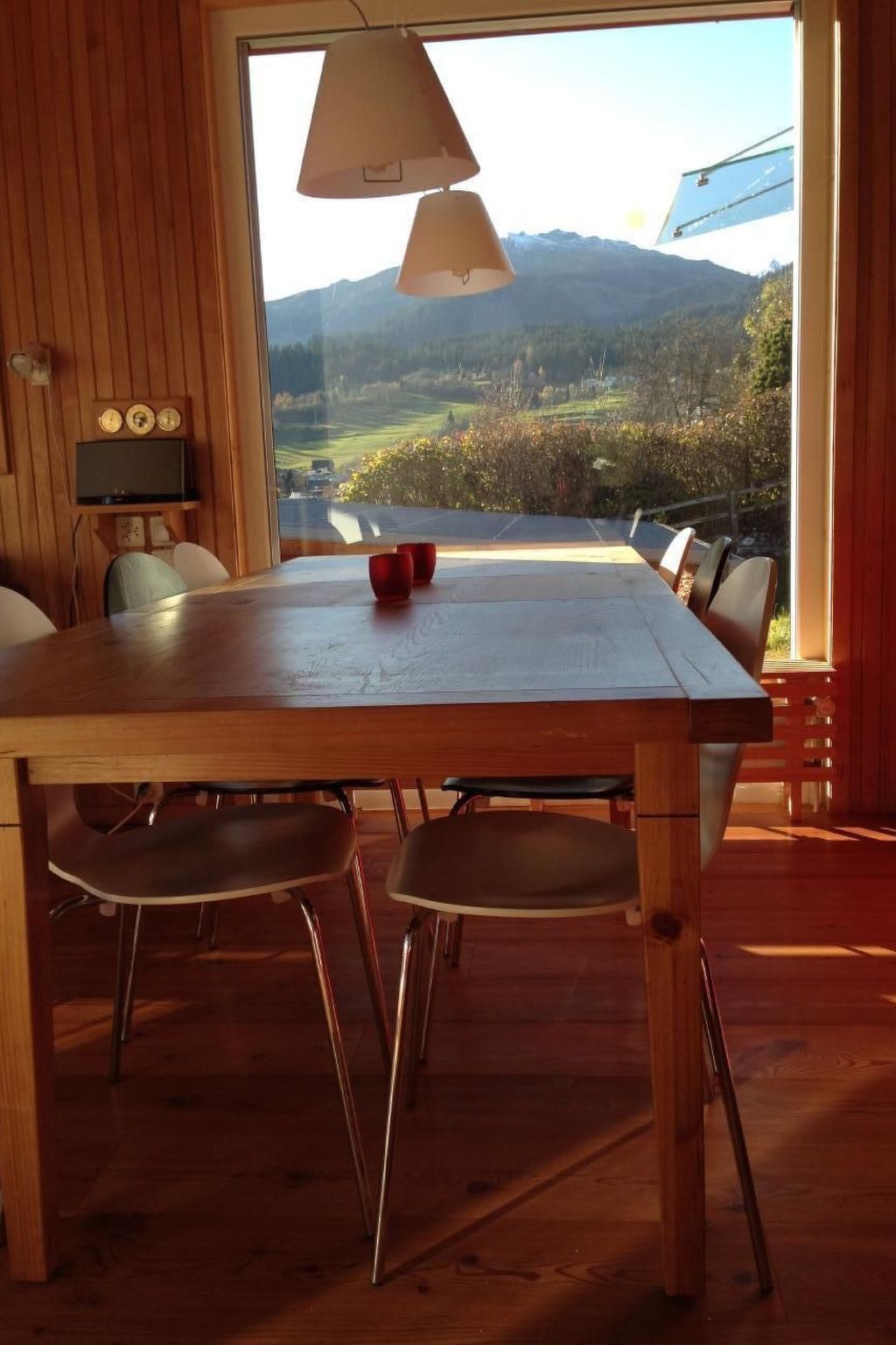 Ein Holzespeisesaal mit vier Stühlen, einem Fernseher an der Wand und Bergblick durch ein großes Fenster.