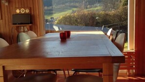 Ein Holzespeisesaal mit vier Stühlen, einem Fernseher an der Wand und Bergblick durch ein großes Fenster.