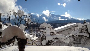 Schneelandschaft mit Bergen im Hintergrund und einem klaren Himmel.