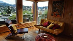 Ein modernes Wohnzimmer mit Holzboden, einer Ledersofa, einem Lederhocker und einer Holzbank.