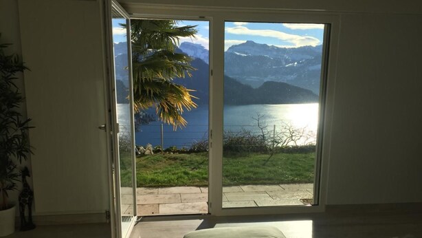 A bedroom with a sliding glass door leading to a balcony with a view of mountains and a lake. - Apartment Weggis by Interhome (Weggis)