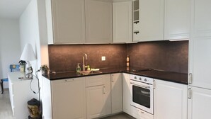 A modern kitchen with white cabinets, a black countertop, and a built-in oven. - Apartment Weggis by Interhome (Weggis)