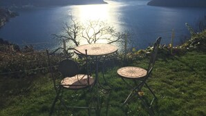 A lakeside view with a table and chairs overlooking a calm lake and mountains. - Apartment Weggis by Interhome (Weggis)