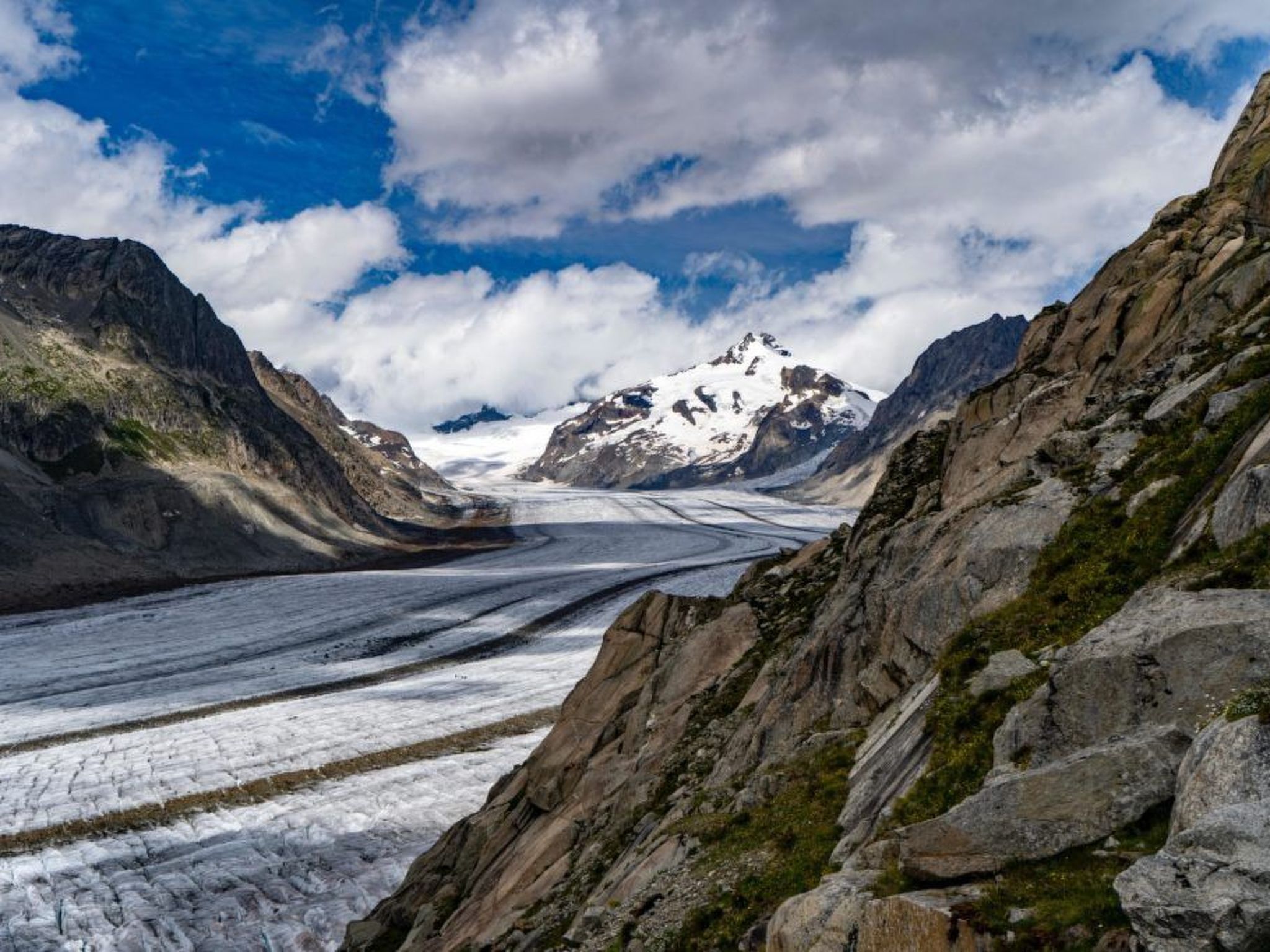 A glacier with rocky terrain and a mountain in the background.