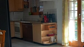 Een keuken met houten kastjes, een koelkast, een koffiezetapparaat en een eettafel met een kaars.