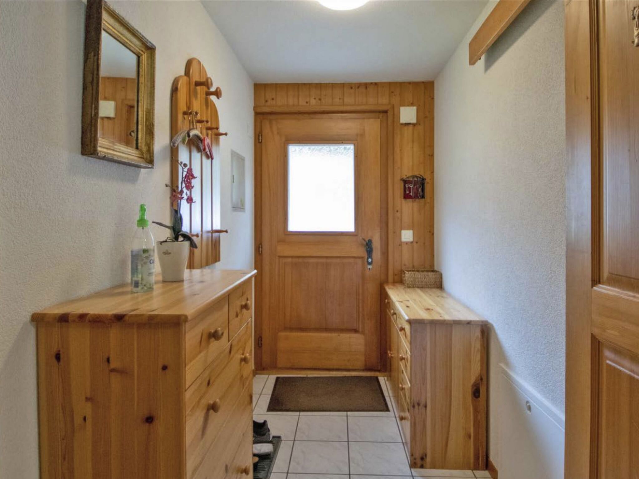 A wooden bathroom with a large mirror, a wooden cabinet, and a small window.
