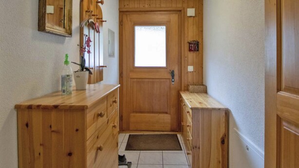 Un bagno in legno con uno specchio grande, un armadietto in legno e una piccola finestra.