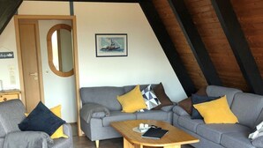 A cozy living room with a grey sofa, a wooden coffee table, and a grey armchair. - Tossi Haus 107 in Fedderwardersiel by Interhome (Burhave)