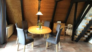 A dining area with a wooden table and chairs, a hanging lamp, and a staircase. - Tossi Haus 107 in Fedderwardersiel by Interhome (Burhave)