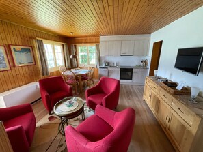 A cozy cabin interior with a dining area, kitchen, and seating with red chairs. - Apartment Plexat by Interhome (Fiesch)