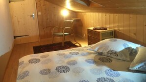 A wooden cabin bedroom with a bed, a chair, a small table, and a nightstand. - Darioli by Interhome (Innertkirchen)