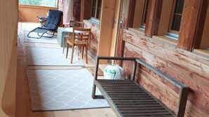 Eine Holzhütte mit einer Veranda, einer Bank und einem Tisch.