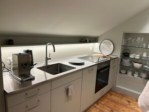 Een koelkast, een oven, een vaatwasser, kookgerei, borden en bestek