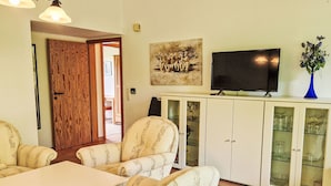 A living room with a white cabinet, a television, and patterned chairs. - K5 Haus in Eckwarderhörne mit Terrasse und Garte by Interhome (Burhave)