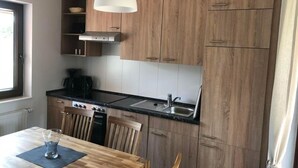 A modern kitchen with wooden cabinets, a black countertop, and a dining area with a table and chairs. - Vacation home  by Interhome (Burhave)