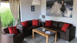 A modern living room with a sofa set, a wooden coffee table, and a painting of a lighthouse on the wall. - Vacation home  by Interhome (Burhave)