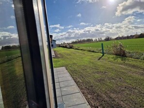A view from inside a building looking out to a grassy field with a small structure in the distance. - G20 Ferienhaus mit Wintergarten in Eckwarderhörn by Interhome (Burhave)