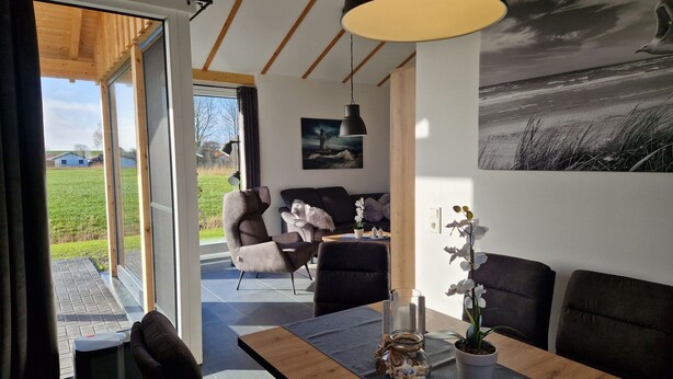 Ein modernes Wohnzimmer mit Essbereich, großen Fenstern und Blick ins Freie.
