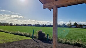Eine Hollaube mit freiem Blick auf ein grünes Feld und entfernte Häuser unter blauem Himmel.