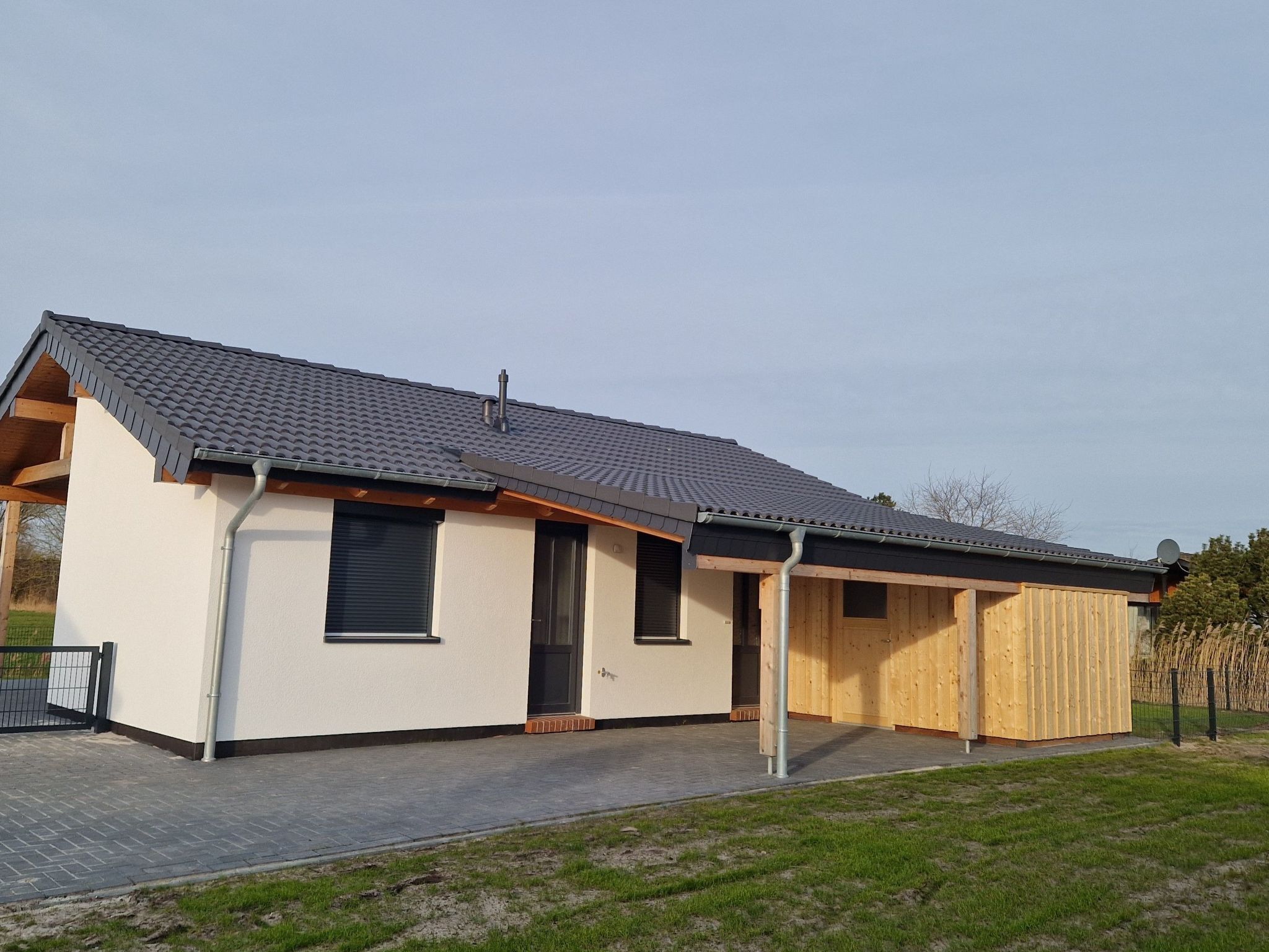 A modern single-story house with a sloped roof, a covered porch, and a paved driveway.