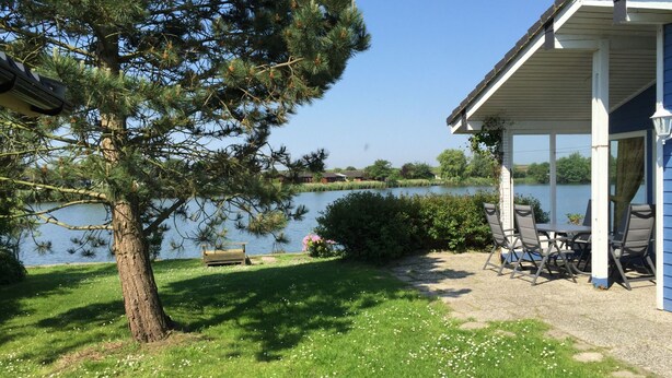 A lakeside property with a covered patio, a dining table, and chairs. - Vacation home  by Interhome (Burhave)