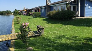 A row of blue houses with a grassy lawn and a body of water. - Vacation home  by Interhome (Burhave)