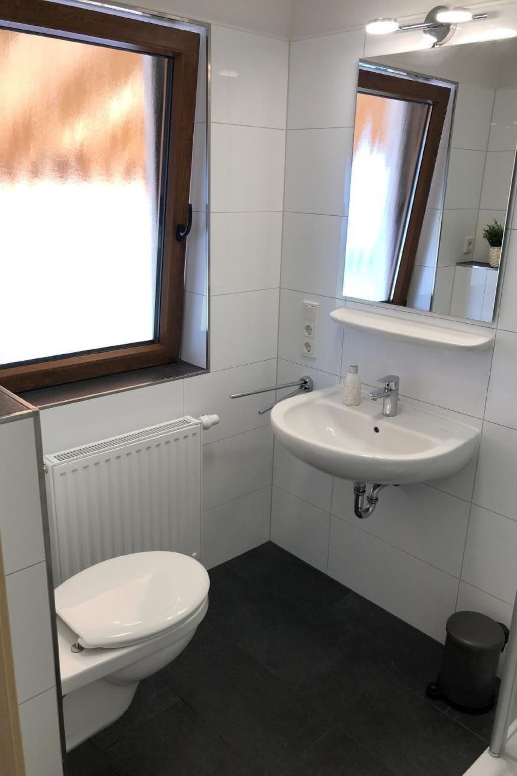 A modern bathroom with a toilet, sink, and window.