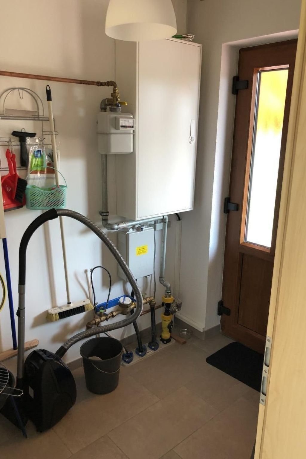 A compact bathroom with a toilet, sink, and shower area. There is a window providing natural light, and a door leading to another room.