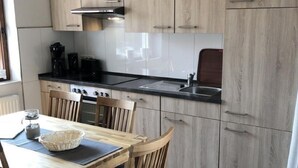 Una cocina moderna con armarios de madera, encimera negra y una mesa de comedor con sillas.