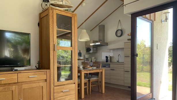 Eine moderne Küche mit Holzausstattung, einem Esstisch und einem großen Fenster.