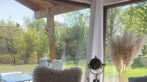 Ein gemütlicher Wohnbereich mit einem weichen Sessel, einer Couch und einem Couchtisch mit Fernbedienung und Dekorationselementen.