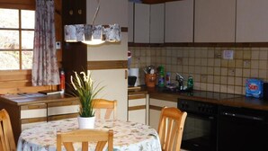 Een knus keuken met houten kastjes, een eettafel met bloemenonderzetter en een potplant.