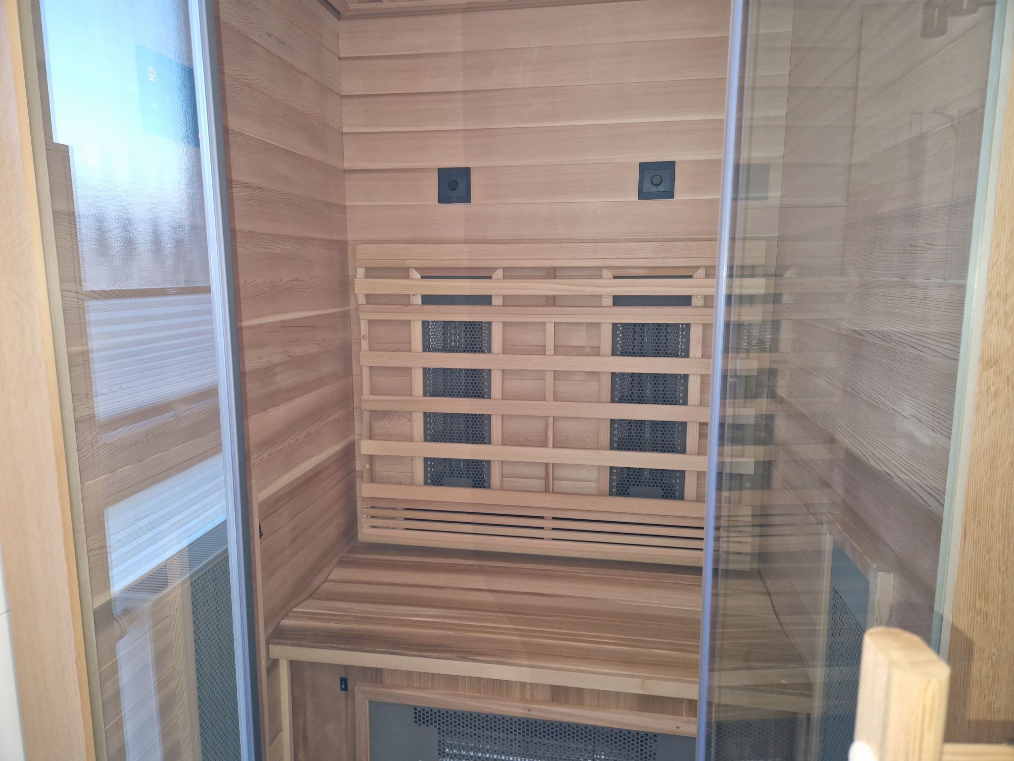 A sauna room with wooden walls and a bench.
