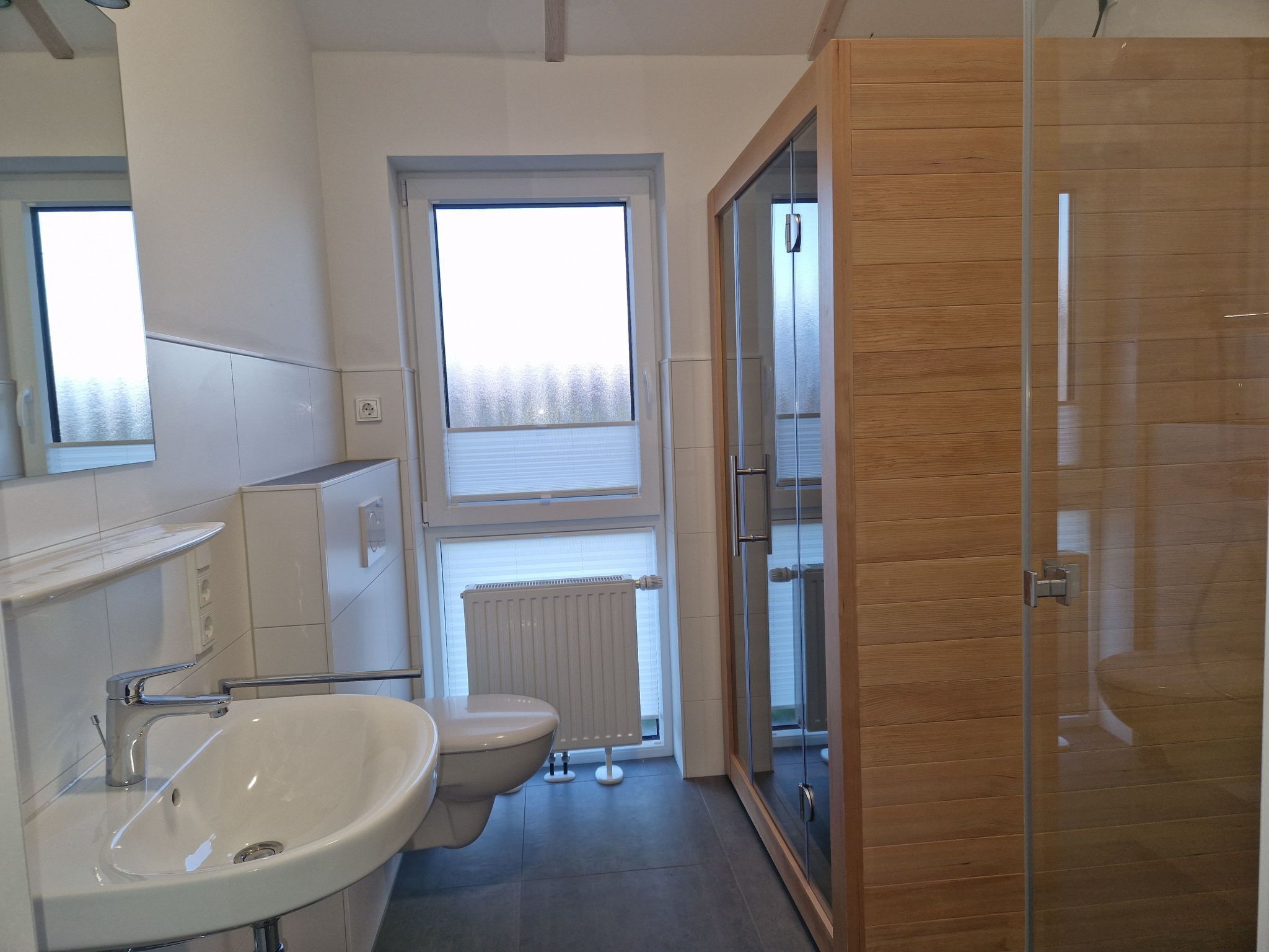 Une salle de bain moderne équipée d’un lavabo, de toilettes et d’une zone douche.