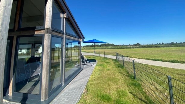 A modern building with large glass windows and a covered outdoor seating area. - Vacation home G30 by Interhome (Burhave)