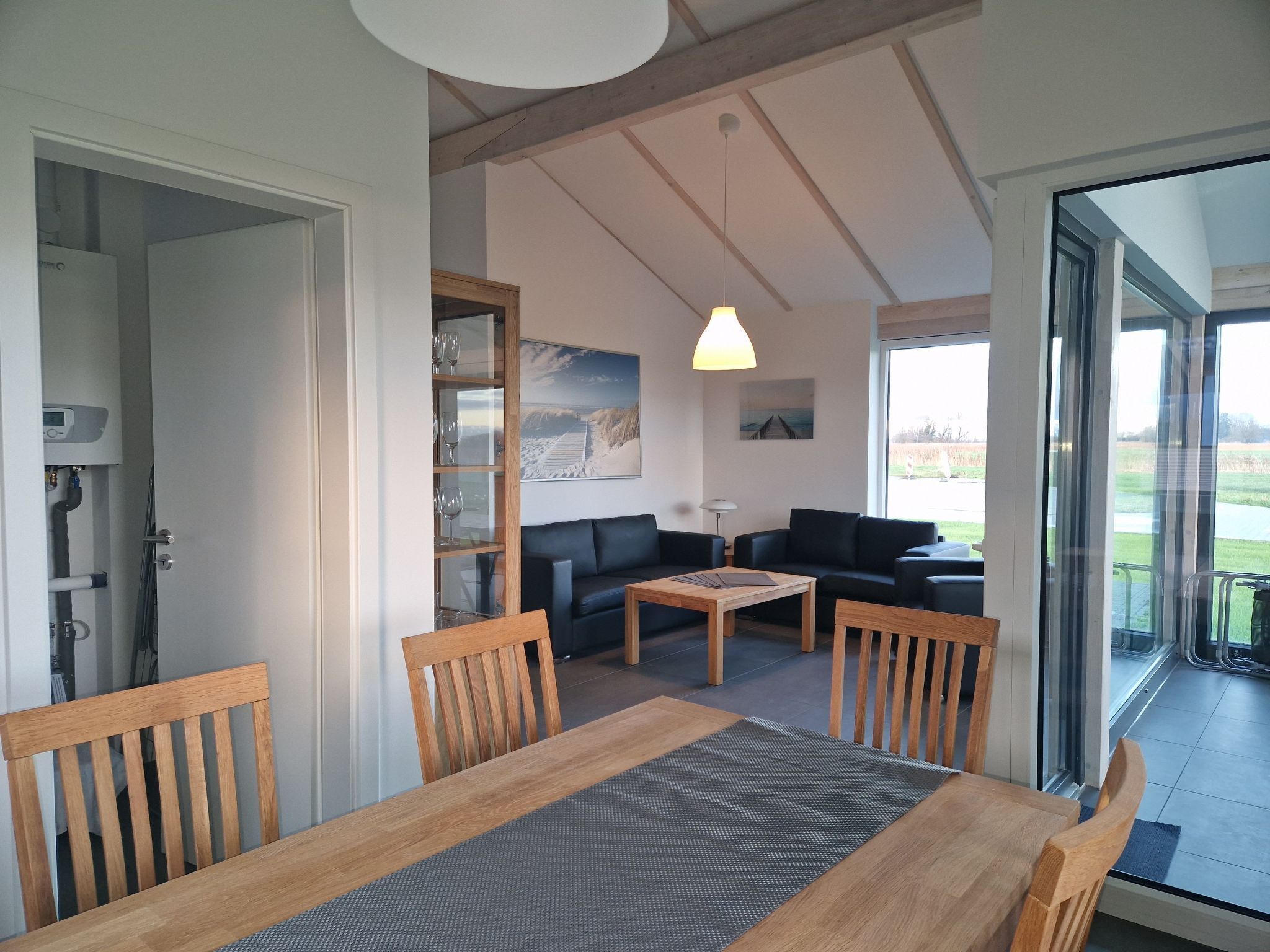 Un coin repas avec une table et des chaises en bois, un canapé et une porte vitrée donnant sur un balcon.