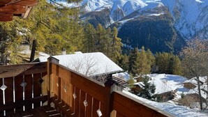 A wooden deck with a view of snow-covered mountains and trees. - Chalet Luisa by Interhome (Bellwald)