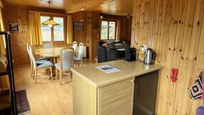 L’intérieur d’un chalet en bois comprend un coin cuisine, une table à manger et des chaises.