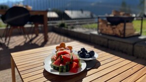 A wooden table with a plate of watermelon and blueberries, a chair, and a barbecue grill in the background. - Wohnung Vieux Valais by Interhome (Bellwald)
