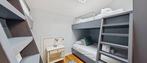 Un dormitorio pequeño con una cama litera, un escritorio y un tragaluz.