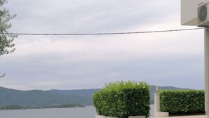 Un césped cuidado con setos y vistas a un lago y colinas al fondo.